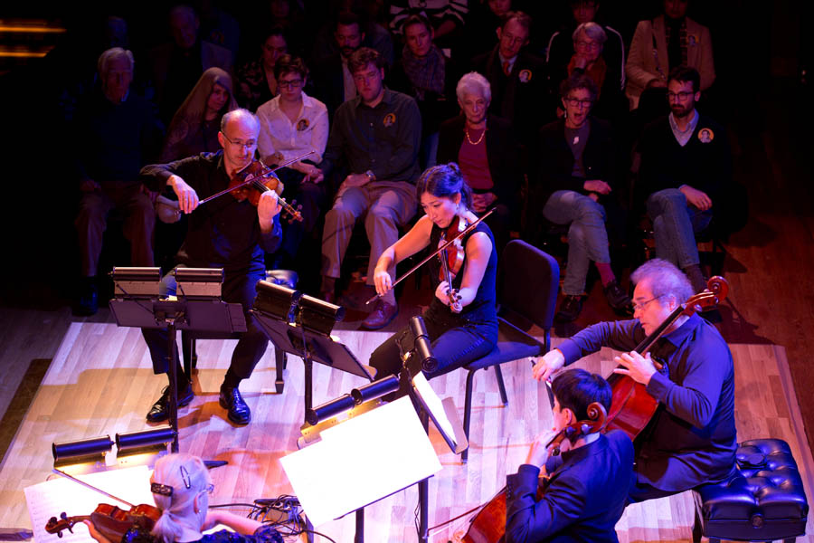 Five musicians performing with string instruments.